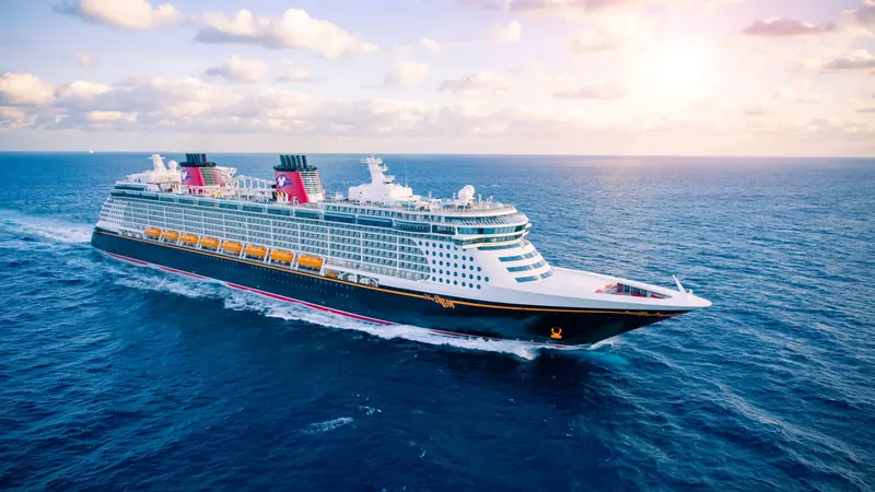 Vista aérea do navio Disney Dream navegando em mar aberto, com espuma na proa