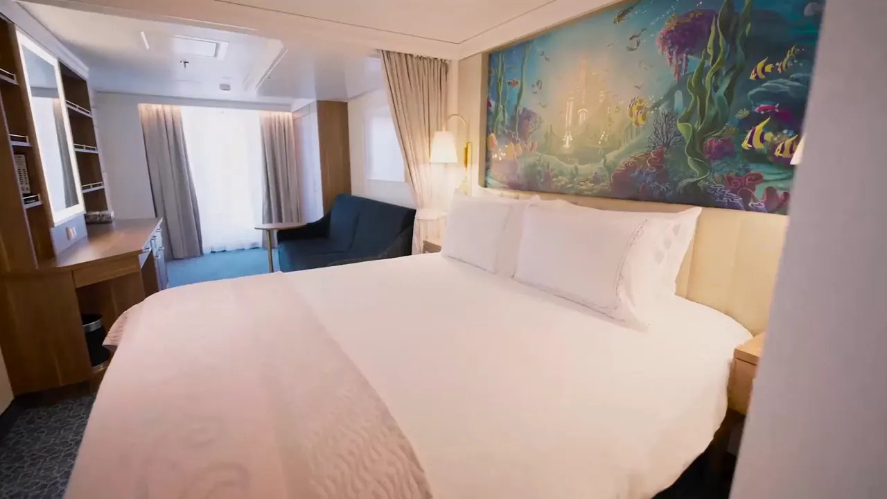 Cabine com cama de casal, sofá e um mural colorido do fundo do mar na parede